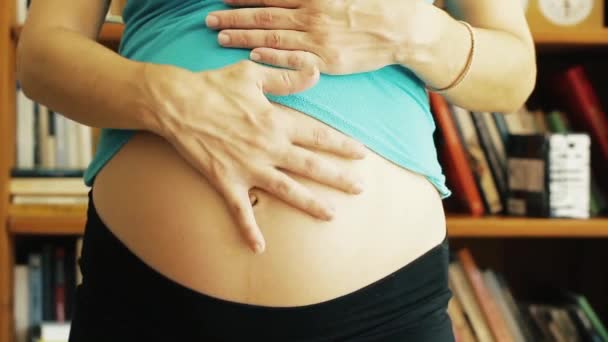 Bauch Einer Schwangeren Frau Über Einem Hintergrund Aus Büchern — Stockvideo