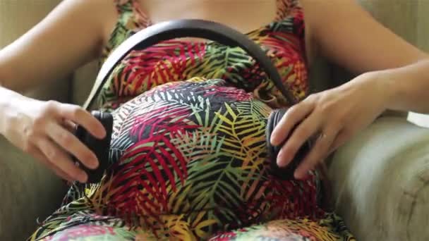 腹部有耳机的年轻怀孕妇女 — 图库视频影像