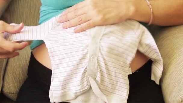 Zwanger Meisje Kijkt Naar Een Baby Jurk Voor Een Pasgeboren — Stockvideo