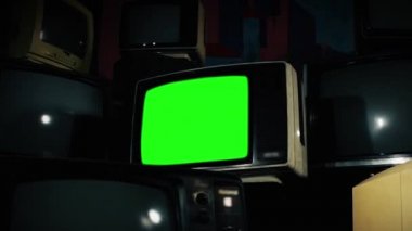 Bir sürü televizyonu olan eski bir televizyon. Uzaklaş. Yeşil ekranı istediğin görüntüyle ya da resimle değiştirebilirsin. Bunu Adobe After Effects ya da diğer video düzenleme yazılımlarında Keying (Chroma Key) efekti ile yapabilirsiniz (Youtube 'daki derslere bakın).