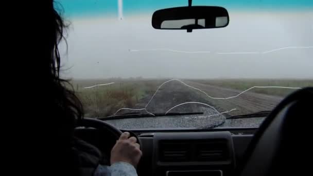 壊れたフロントガラスの古い車で田舎の畑の未舗装道路を運転する女性 — ストック動画