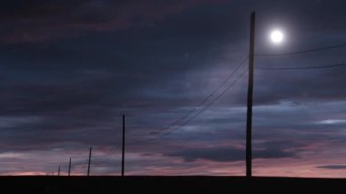 Kırsal bir alanın elektrik direkleri ve kabloları üzerinde gün batımı. Yakınlaştır. 