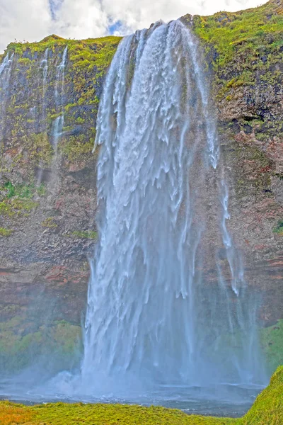 Тенистый водопад, ревущий над скалой — стоковое фото