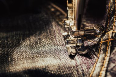 Kot dikiş makinesi tamir. Kumaş, iğne ve iplik görünümü. Yerleşik akkor lamba aydınlatma. Kot pantolon, genellikle kot veya dungaree kumaştan yapılmış bir türüdür