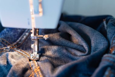 Kot dikiş makinesi tamir. Kumaş, iğne ve iplik görünümü. Yerleşik akkor lamba aydınlatma. Kot pantolon, genellikle kot veya dungaree kumaştan yapılmış bir türüdür