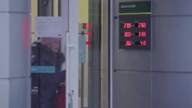 Dnipro, Ukrayna - 27 Aralık 2018: Yaşlı bir kadın Oschadbank şube kapı dışarı geliyor. Döviz kuru dolar ve Euro ile ilgili olarak Ukraynalı hryvnia işaretiyle parlayan