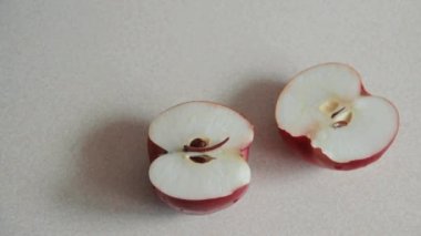 Erkekler elleri kesilmiş kırmızı elma su damla mutfak masası üzerinden iki yarısı alarak dönüşümlü olarak. Vejetaryenler meyve öğle yemeği için seçin. Yukarıdan görüntüleyin. Düz yatıyordu.