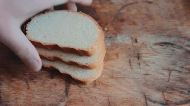 男性の手は 鉄製のナイフと木製キッチンまな板の上の白パンのカット部分を二等分します 朝食用のパンを提供しています 上からの眺め クローズ アップ — ストック動画