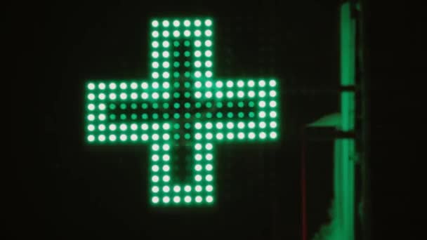 在24小时药店网络上 户外闪烁引领绿色交叉动画标志 冬天夜街建筑中的药学符号 城市药店 有急救保健用品 — 图库视频影像