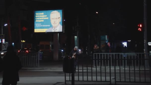 乌克兰第聂伯罗 2019年2月11日 照明广告牌 总统候选人阿纳托利 格里森科的广告竞选活动 晚上的街道 人行横道 人们过马路 交通灯 — 图库视频影像