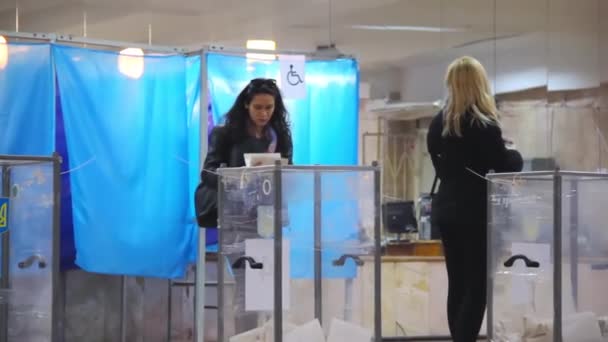 Jonge brunette vrouwelijke kiezer zet het stembiljet in de stembus — Stockvideo