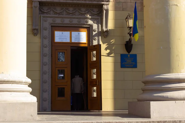 DNIPRO, UCRÂNIA - 31 de março de 2019: Entrada para o local da estação de votação no prédio da universidade. Eleição do Presidente da Ucrânia. Bandeira ucraniana voando perto da porta — Fotografia de Stock