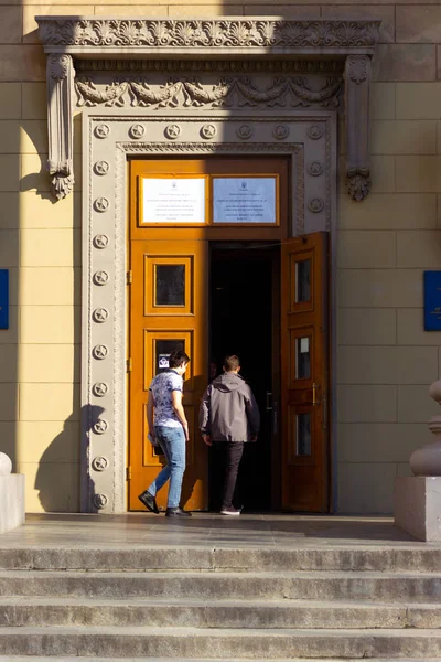 DNIPRO, UCRANIA - 31 de marzo de 2019: Personas en la entrada al lugar del centro de votación en el edificio de la universidad. Elección del Presidente de Ucrania. Bandera de Ucrania volando cerca de la puerta —  Fotos de Stock