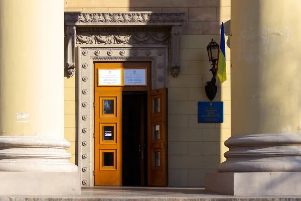 DNIPRO, UCRÂNIA - 31 de março de 2019: Entrada para o local da estação de votação no prédio da universidade. Eleição do Presidente da Ucrânia. Bandeira ucraniana voando perto da porta — Fotografia de Stock