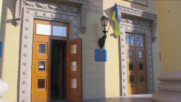 La bandiera nazionale ucraina sventola sull'ingresso al seggio elettorale nell'edificio universitario durante le elezioni presidenziali in Ucraina nel 2019. Lampione nelle vicinanze. Giorno di marcia soleggiato — Video Stock