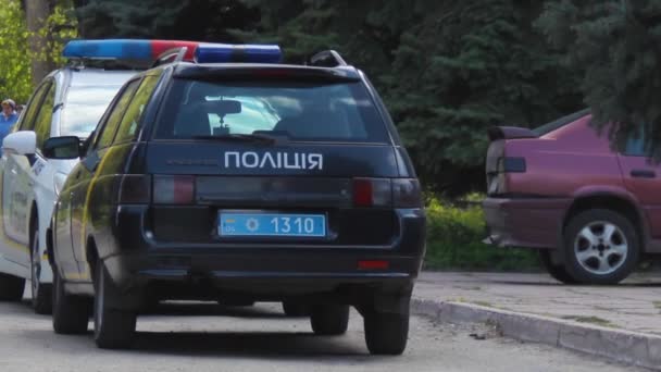 Zwei Polizeiautos sind unterwegs. Ältere Frau mit einem Jungen geht — Stockvideo