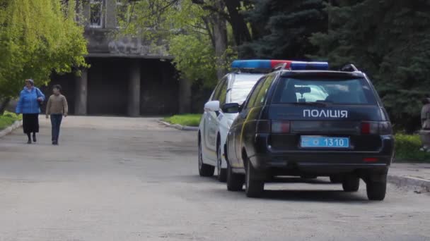 Two police cars are on the road. Elderly woman with a boy walks — Stock Video