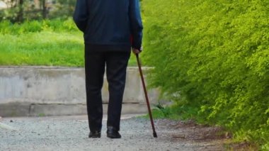 Baharda sokakta değnek olan yaşlı bir adamın silueti