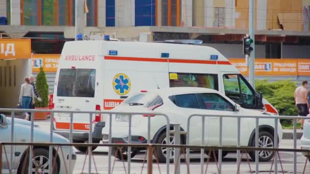 En ambulans bil vänta vid ett vägskäl framför en fotgängare — Stockvideo