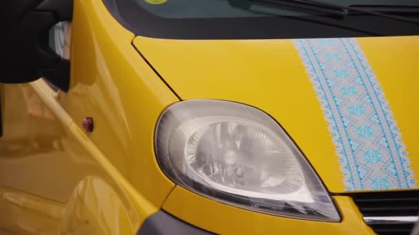 Gelber Minivan mit Applikation auf der Motorhaube in Form vishivanka — Stockvideo