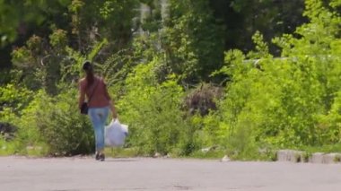 Genç bir kız çanta ile yolda bir bakkal dışarı yürüyor