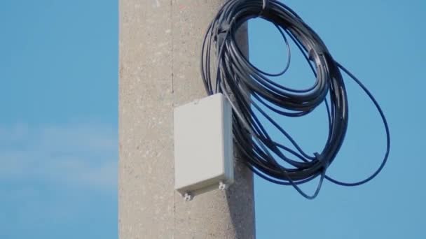 Černý elektrický kabel s kroužkem na železobetonovém pilíři na obloze