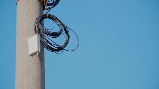 Cable eléctrico negro anillado en poste de pilar de hormigón en el cielo azul — Vídeo de stock