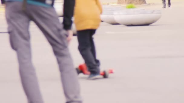 Ein kleiner Junge in einer gelben Jacke auf einem Motorroller. — Stockvideo