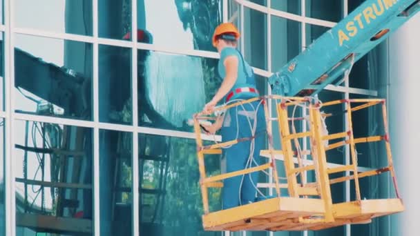 Hombre trabajador limpiador de vidrio en un ascensor hidráulico lava ventana — Vídeos de Stock