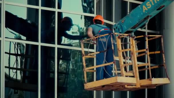 Hombre trabajador limpiador de vidrio en una ventana de limpieza elevador hidráulico — Vídeos de Stock