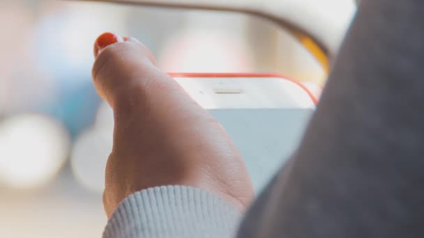 Una ragazza con una camicetta a maglia leggera tiene in mano un telefono cellulare — Video Stock