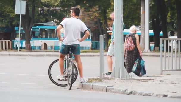 Chlápek s kolem na křižovatce ulice s hustým provozem — Stock video