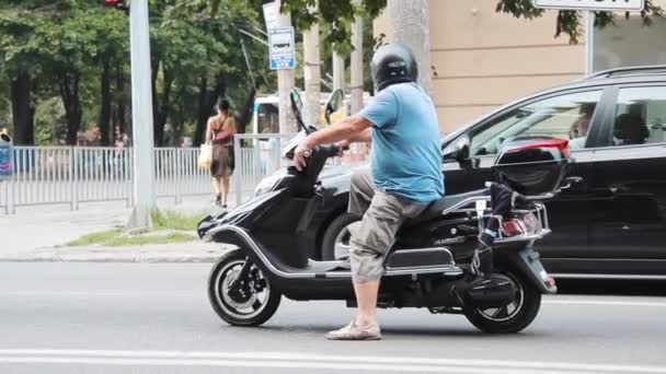 Motosikletli koruyucu kasklı bir adam yeşil ışıkta sürmeye başlıyor. — Stok video
