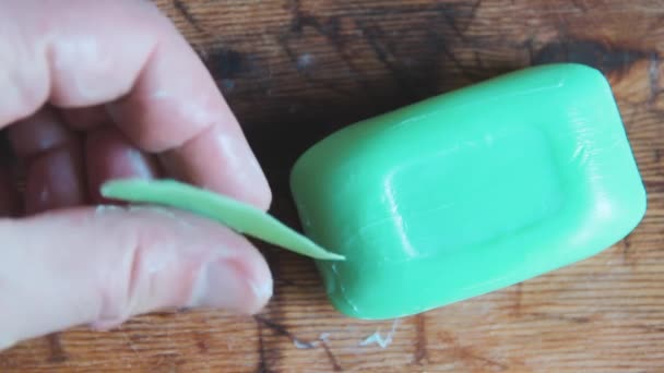 Gehydrateerde mensenhand houdt kleine restanten van groene zeep vast. Steekt een stuk zeep — Stockvideo