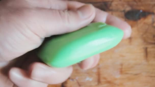 Egy férfi egy darab zöld szappant tart a nedves tenyerében. Kéz a kézben. Fürdőház — Stock videók