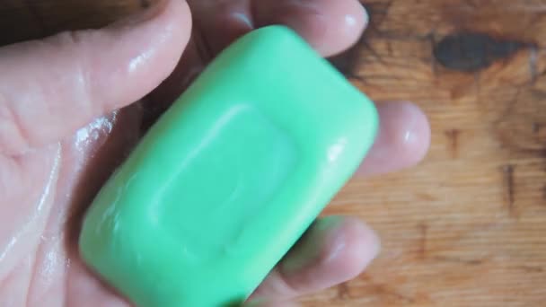 Un uomo tiene un pezzo di sapone verde in una palma bagnata. Lathers mano . — Video Stock