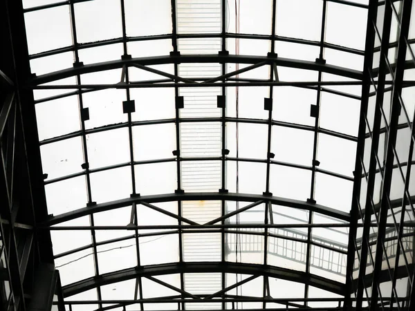 Acristalamiento de obra abierta del techo sobre el centro comercial. Techo en forma de arco de acero con ventanas de cristal. Vista inferior en un día nublado —  Fotos de Stock