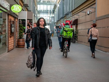 Moskova, Rusya - 14 Eylül 2019: Delivery club sırt çantasıyla kurye, yoldan geçenler arasında sokak alışveriş merkezinde bisikletsürüyor. Kafe ve restoranlardan yemek dağıtan termal çanta şirketi