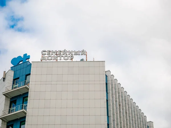 Moscú, Rusia - 14 de septiembre de 2019: Edificio con baldosas ligeras. En la parte superior es médico de familia pagado logotipo de la red clínica privada y el corazón azul y el símbolo de la cruz combinados juntos . — Foto de Stock