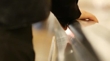 Yürüyen merdiven tırabzanındaki bir yolcunun el kaldırışı. Siyah kauçuk tırabzanda yürüyen bir kadın el.