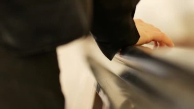 Yürüyen merdiven tırabzanındaki bir yolcunun el kaldırışı. Kadınlar siyah kauçuk tırabzanlara tırmanıyor.