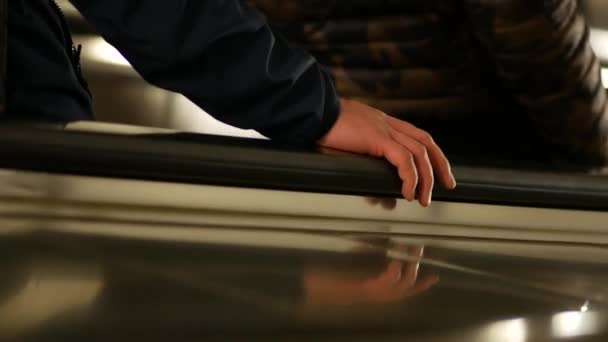 Closeup of a two passengers lifting on escalator. Human hand on handrail. — Stock Video