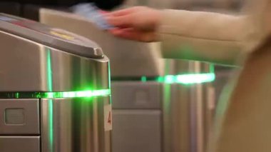 İnsanlar metroda yürürler. Kadın eli plastik kart kullanıyor.