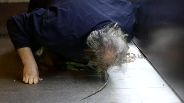 Homem idoso afundou no pavimento e procura dinheiro caído e moedas rolantes — Vídeo de Stock