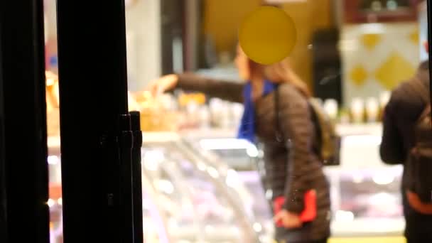 Los compradores van y vienen a través de las puertas de una pequeña tienda de comestibles callejeros por la noche — Vídeo de stock