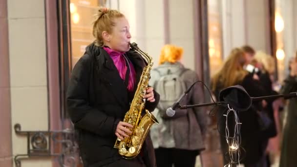 Vrouw die saxofoon speelt. De avond stad flikkert met de lichten — Stockvideo