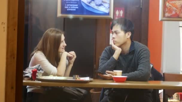 Casal namoro. Cara e menina estão sentados a uma mesa em um café de rua — Vídeo de Stock