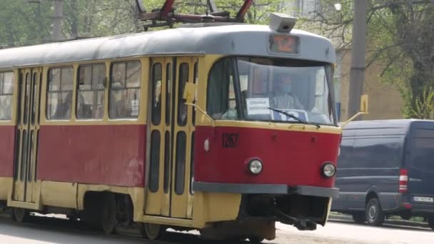 Tram with passengers arrives at a public transport stop in a stream of cars on — Stock Video