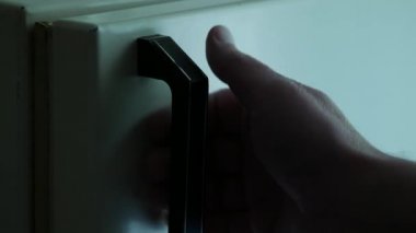 Erkek eli buzdolabının kapı koluna dokunuyor. Eski püskü bir buzdolabı.
