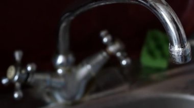 Mutfak musluğu ve lavabo mutfakta. Erkek suyu düğmeyi çevirir ve musluğu açar